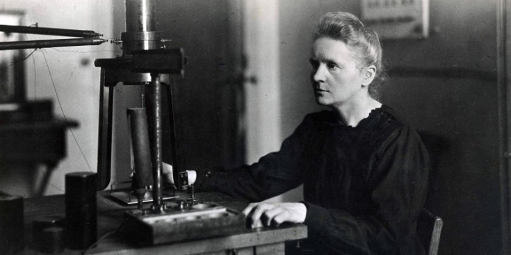 Marie Curie davant d’un microscopi en una de les seves recerques científiques.