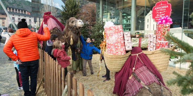 Un grup d’infants acaricia els camells carregats de regals que s’han exposat al Poblet de Nadal, ahir a la tarda.