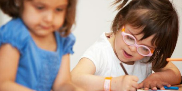Dues nenes escrivint una carta amb un dibuix en el seu pupitre de l’aula escolar.