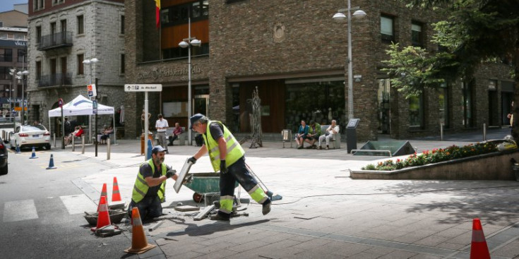 Uns operaris treballant per arreglar els desperfectes de la pluja davant del Comú d’Andorra la Vella, ahir.