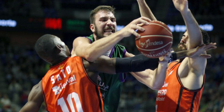 Musli atrapa un rebot entre dos jugadors del València en el partit de la Lliga Endesa disputat al Martín Carpena.