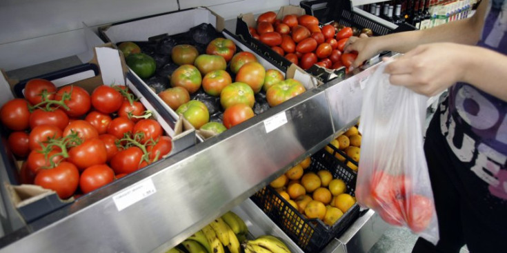 Una dona compra tomàquets en un establiment.