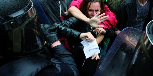 La policia espanyola intenta desallotjar un grup de persones concentrades davant d’un col·legi electoral.