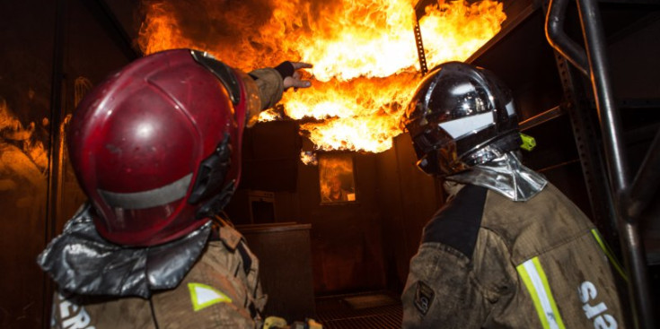 Isaac Lax i un bomber practiquen l’extinció d’un foc.