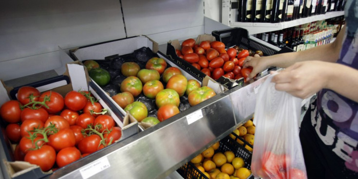 Una persona compra fruita i verdura en un supermercat.