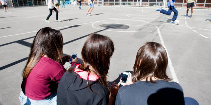 Un grup de noies utilitzen el mòbil durant l’hora de pati.