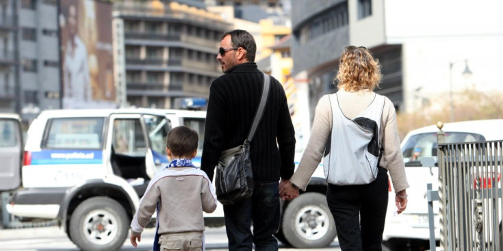 Un nen de la mà del seu pare passeja amb la seva família pels carrers de la capital.