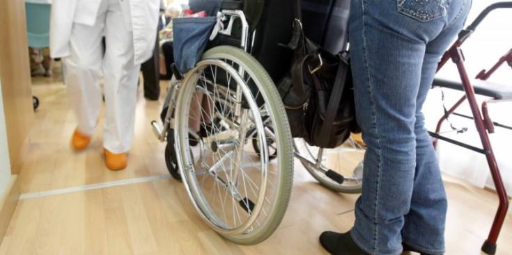 Una persona porta al seu familiar amb cadira de rodes en un centre assistencial del país.