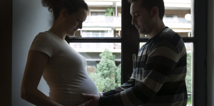 Una parella contempla la panxa de la dona embarassada.