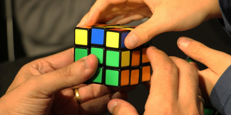 Diferents mans fent un cub de Rubik.