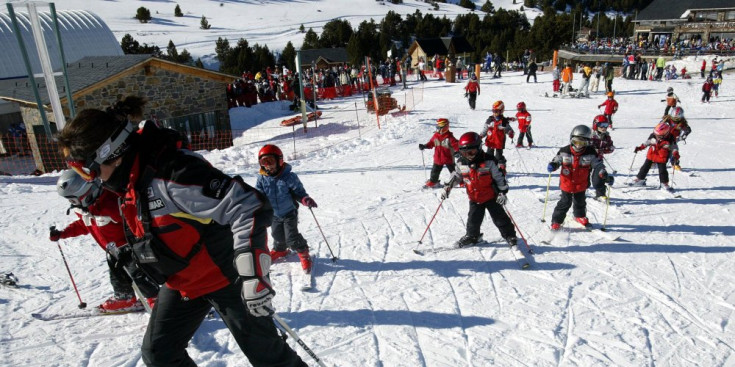 Una monitora amb un grup de petits esquiadors.