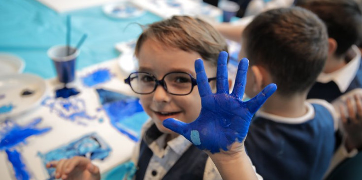 Un nen amb la mà pintada de blau.