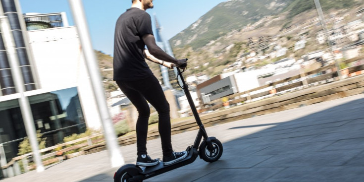 Un home circula amb un patinet elèctric.