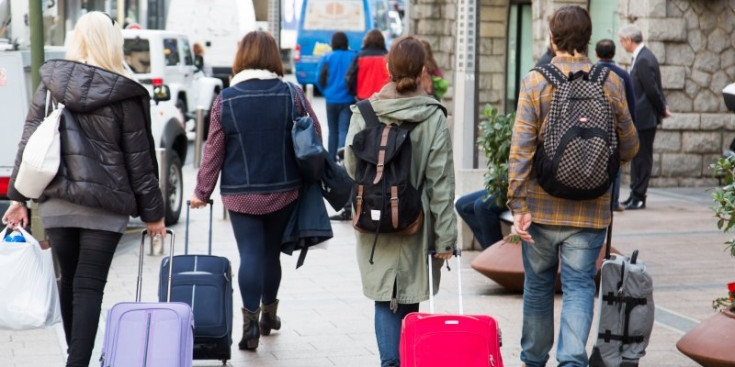Turistes passejant amb el seu equipatge en mà.