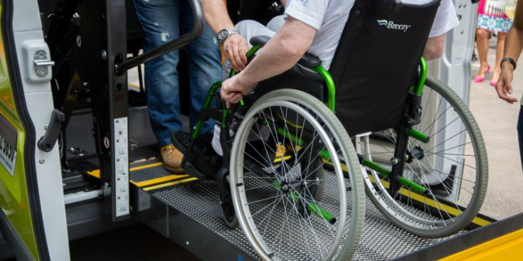 Una persona sense mobilitat puja a un vehicle adaptat per al seu trasllat.