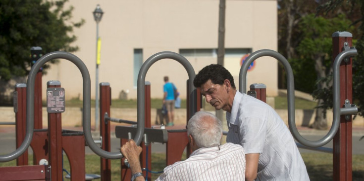 Un home ajuda a un altre a exercitar-se en un parc.