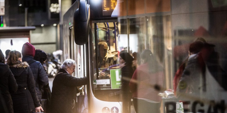 Una dona puja a l’autobús mentre altres usuaris fan cua darrere seu per agafar el mateix transport.