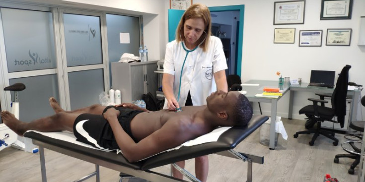 La doctora escolta els batecs de Moussa Diagne mitjançant un estetoscopi.