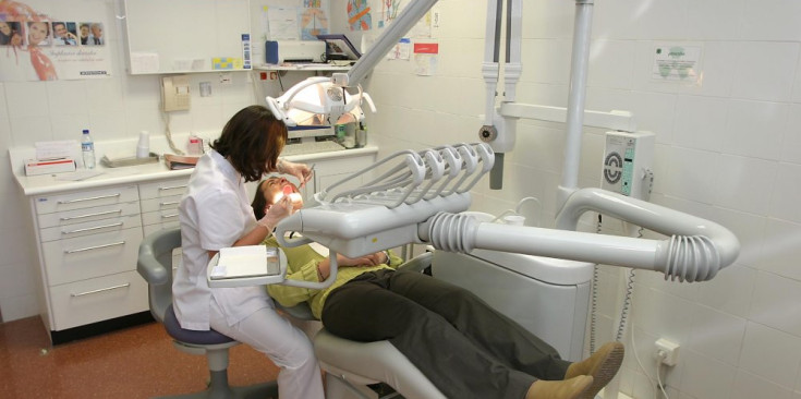 Una dentista atén un pacient en una consulta.