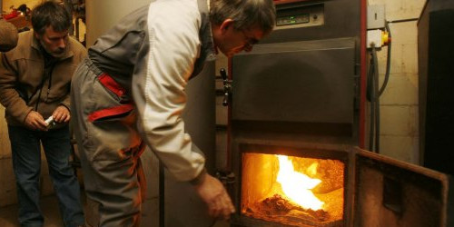 Un operari ensenya el funcionament d’una caldera que funciona amb biomassa estelles de fusta.