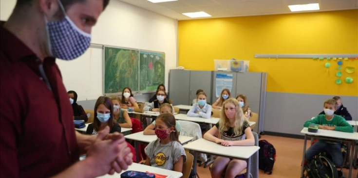 Mestre i alumnes amb mascareta en una aula.