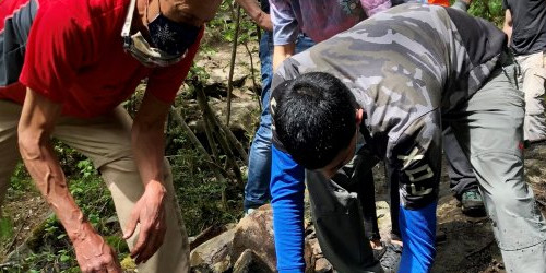 L’instructor Roger Solé ensenyant a un dels joves a com desplaçar una de les pedres.