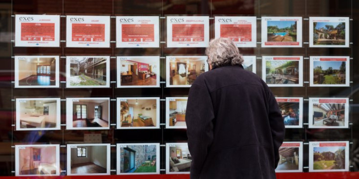 Una persona mira l’oferta de pisos a l’aparador d’una immobiliària.