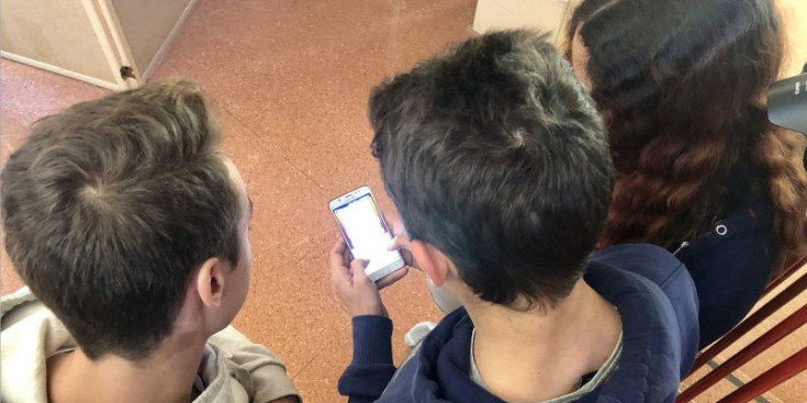 Alumnes d’una escola amb un telèfon mòbil.
