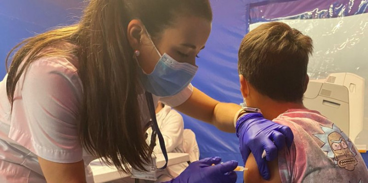 Una infermera vacuna un jove.