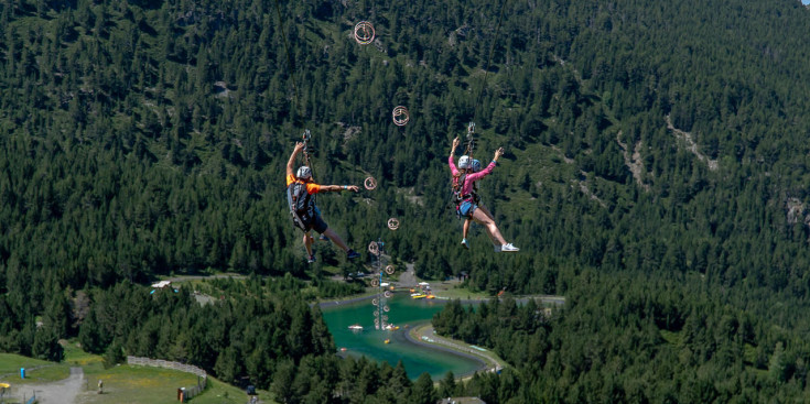 Dos turistes baixant per la tirolina situada al Mon(t) Magic de Canillo.