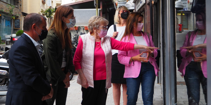 La ministra de Cultura i Esports, Sílvia Riva, el cònsol major de Sant Julià de Lòria, Josep Majoral, i Remei Carmen Obiols Ribó (Carmen de Cal Terrissaire) davant l'aparador de la botiga Isidre Planes.