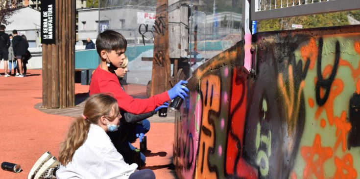 Infants col·laborant en la creació del mural de grafiti a l’skate parc de la Serradora, ahir