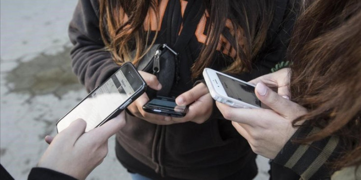 Uns adolescents fan ús del telèfon mòbil.