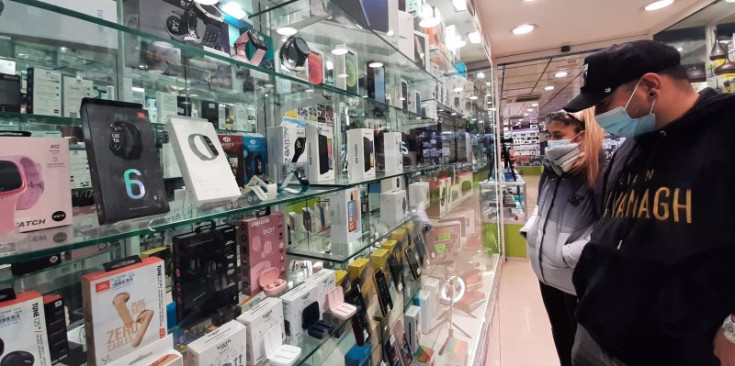 Uns turistes mirant diferents productes de telefonia a l’aparador d’una botiga d’electrònica de l’avinguda Meritxell.