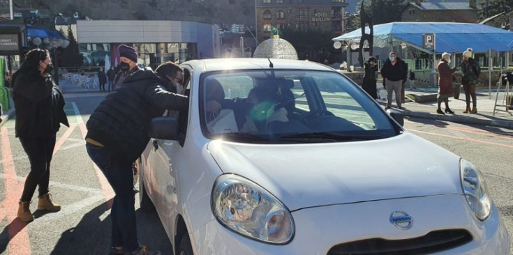 Un tècnic del comú repartint racions d’escudella a un vehicle.