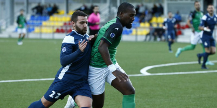 El jugador del FC Santa Coloma Xisco Martínez pressiona el golejador del Sant Julià Bacari en el clàssic viscut a la jornada 5.