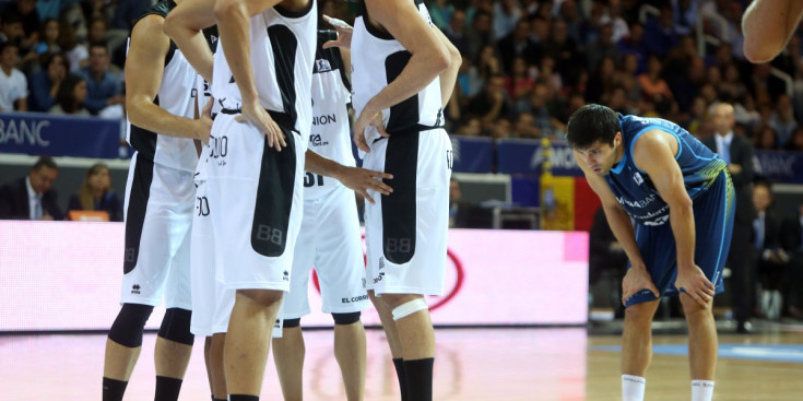 Vojdan Stojanovski espera a la línia de tirs lliures per fer uns llançaments, mentre els jugadors del Bilbao Basket es reuneixen per fer una breu reunió d’equip, ahir al Poliesportiu.