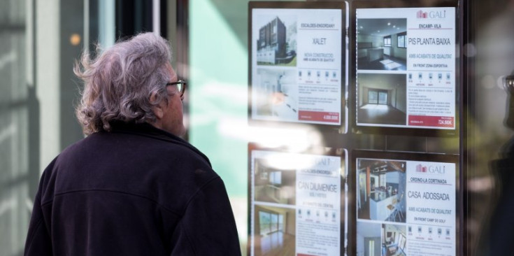 Un ciutadà mira les ofertes disponibles a l’aparador d’una immobiliària.