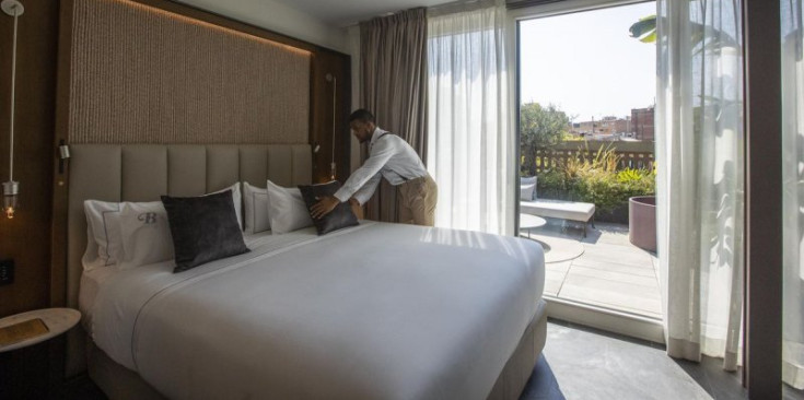Un treballador prepara l’habitació d’un hotel.