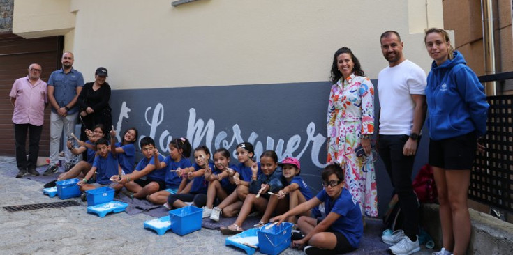 Els infants que han pintat el mural amb la cònsol, els consellers i la muralista.