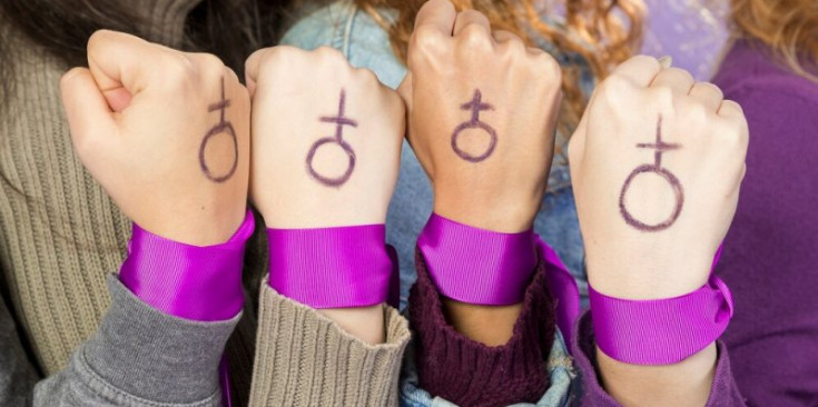 Una imatge de quatre dones amb el símbol feminista dibuixat a la mà.