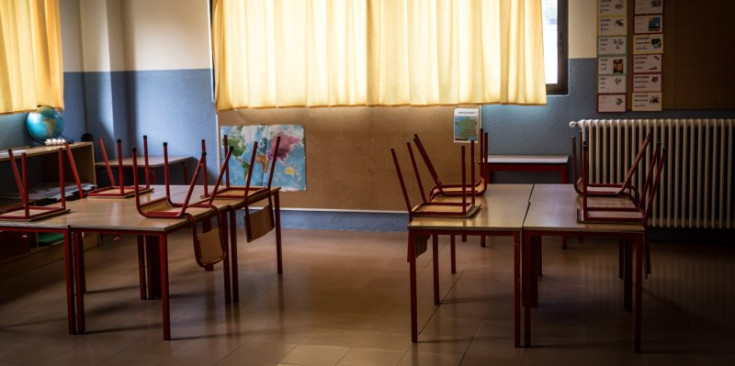 Una aula buida d’una escola del país amb les cadires a sobre de les taules.