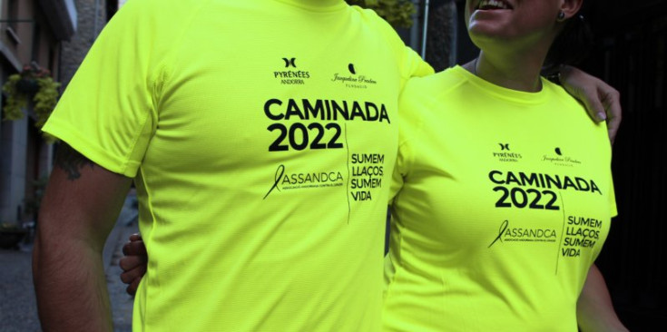 Dues persones amb la samarreta de la Caminada contra el càncer 2022.