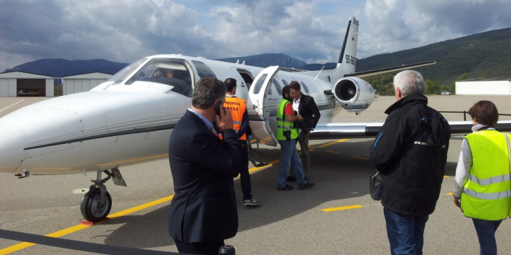 Una avioneta amb la seva tripulació a peu de pista a l’aeroport d’Andorra-Pirineus (esquerra) i la torre de control de les instal·lacions aeroportuàries entre els municipis e Montferrer-Castellbó i Ribera d’Urgellet, a la comarca de l’Alt Urgell.