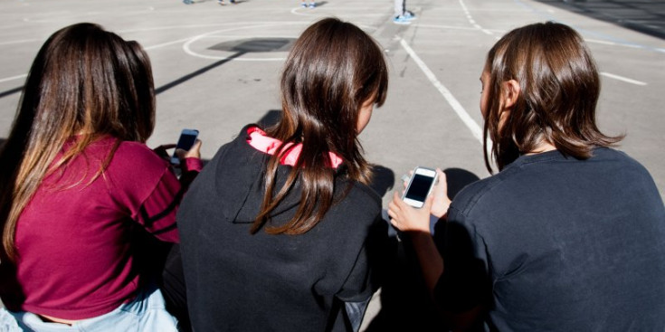 Unes joves s'estan amb els seus dispositius mòbils a l'hora del pati.