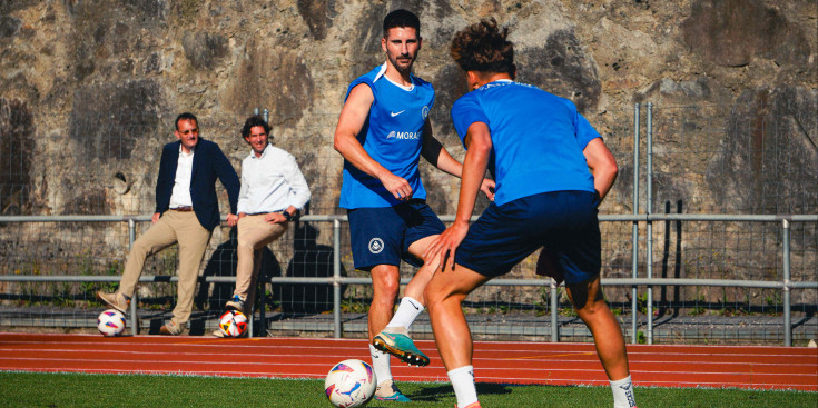 Un entrenament de pretemporada de l'FC Andorra sota la mirada de Ferran Vilaseca i Jaume Nogués, al fons.