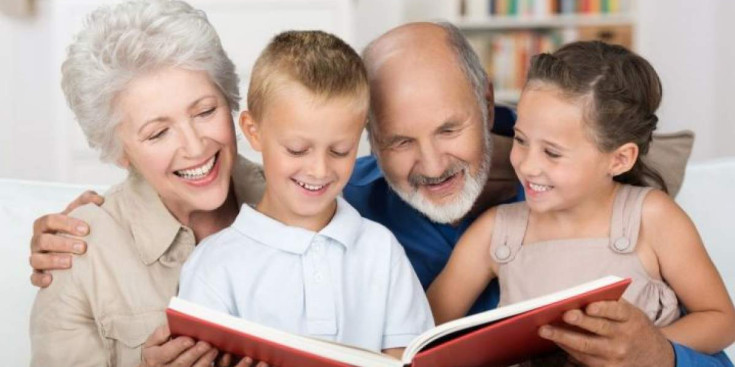 Un avi i una àvia amb els seus nets llegint un conte.