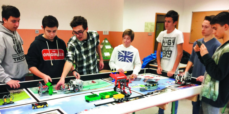 Un equip de joves participants a la First Lego League, amb els robots superant proves a la taula de jocs.