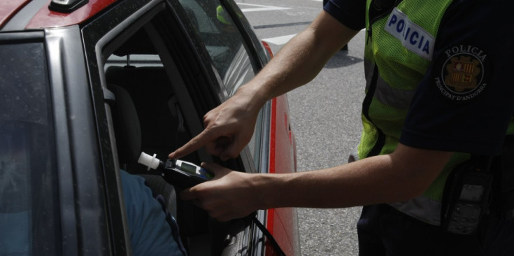 Un agent de policia realitza un control d’alcoholèmia a un conductor.