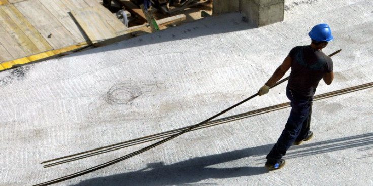 Un treballador de la construcció trasllada uns ferros en una obra.